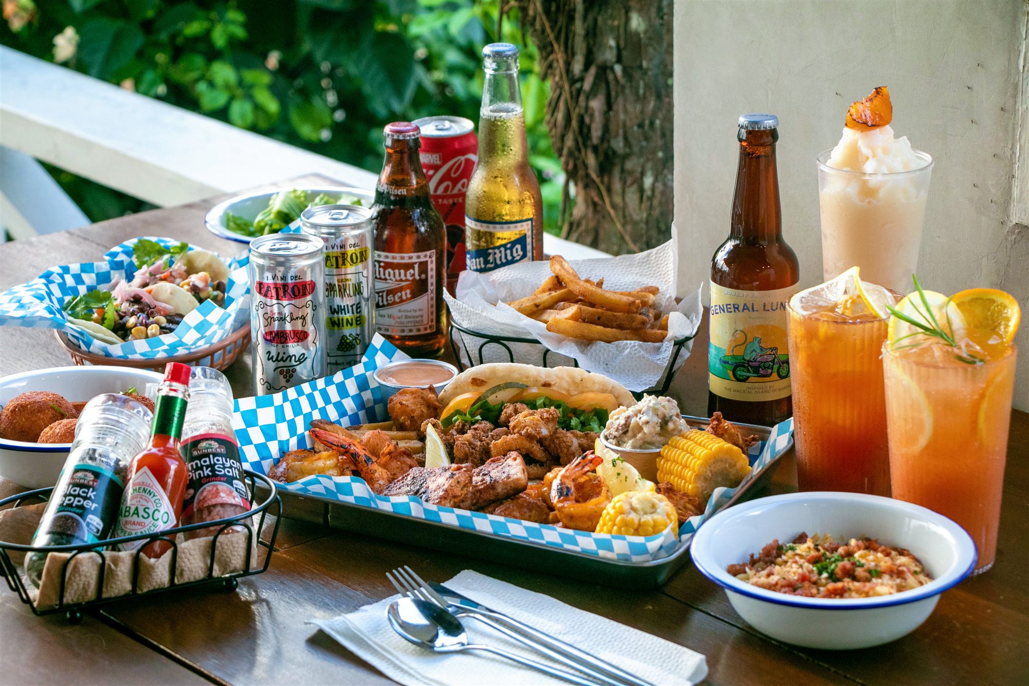 A spread of fresh seafood, fried platters, tacos, fries, and cold drinks on a table in General Luna, Siargao